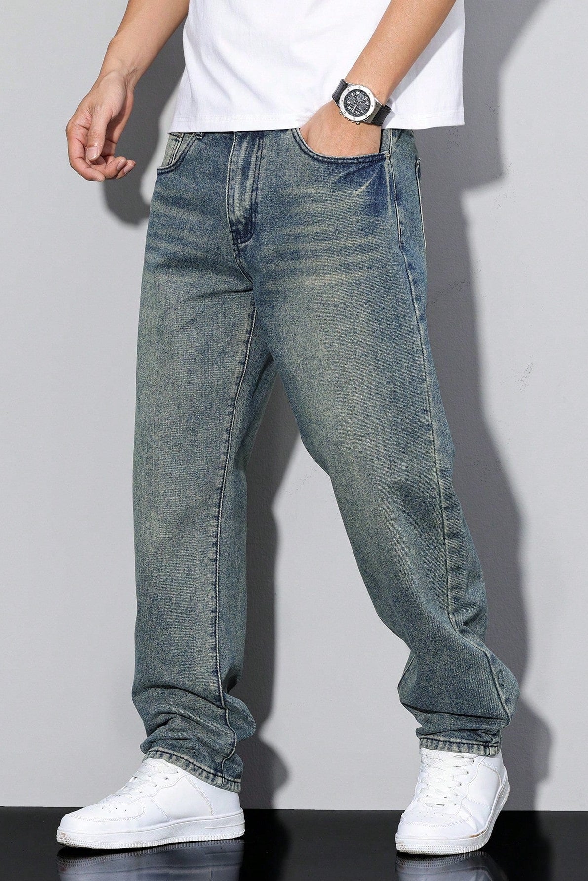 Model wearing the vintage-wash blue jeans with a greenish tint, hand in pocket, with white trainers 6