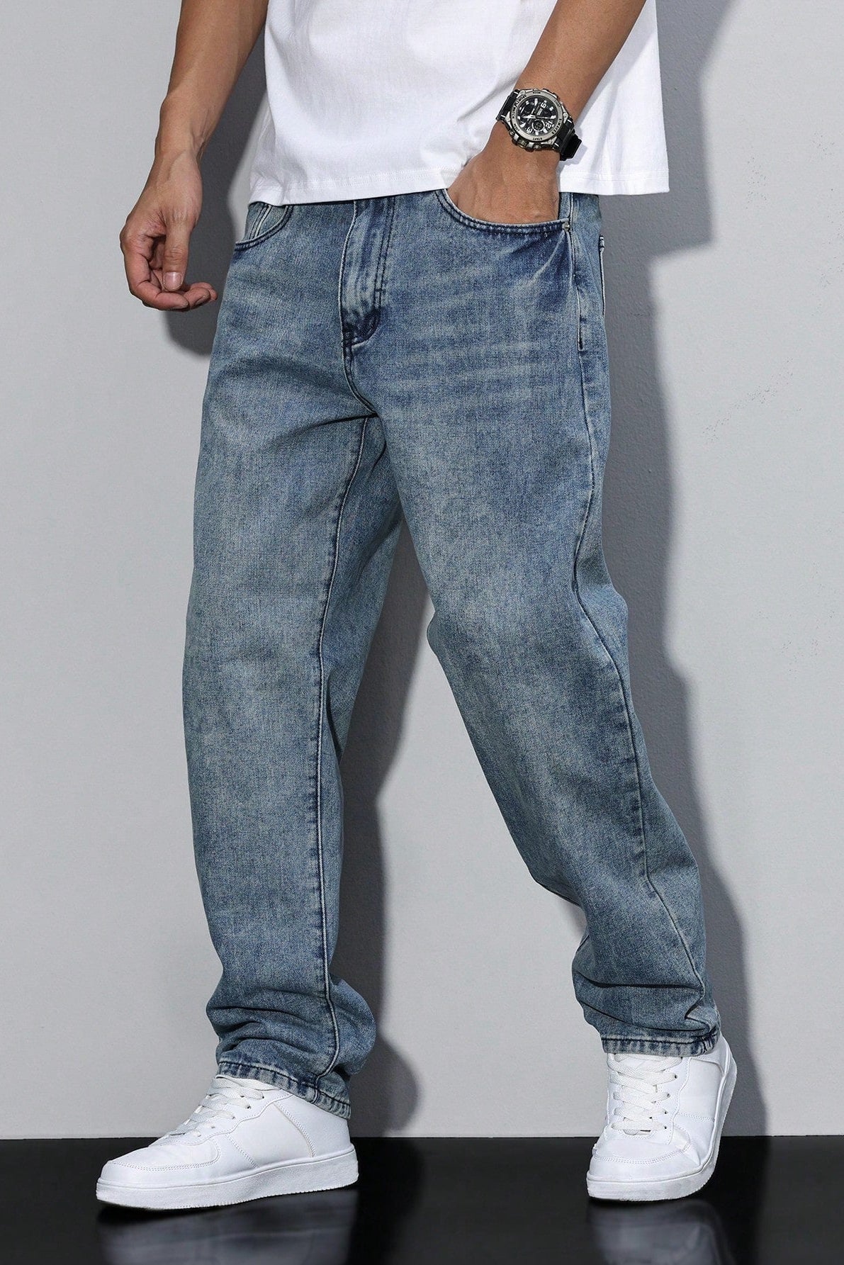 Model wearing a mid-blue acid-wash pair, one hand in the pocket, with a white tee and trainers 7