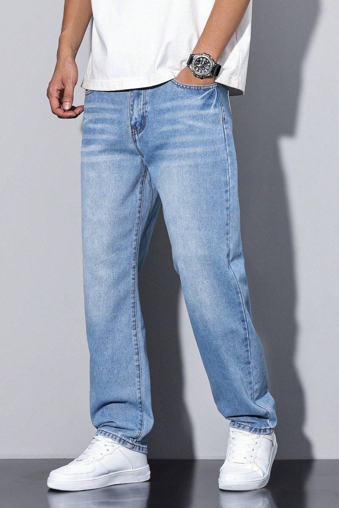 Model wearing the light blue washed pair with a loose white tee, white trainers and a sports watch 8