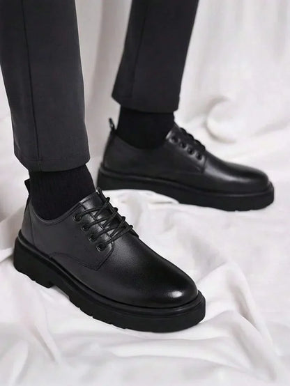 Black lace-up derby shoes worn with dark trousers and black socks, standing on white fabric 1