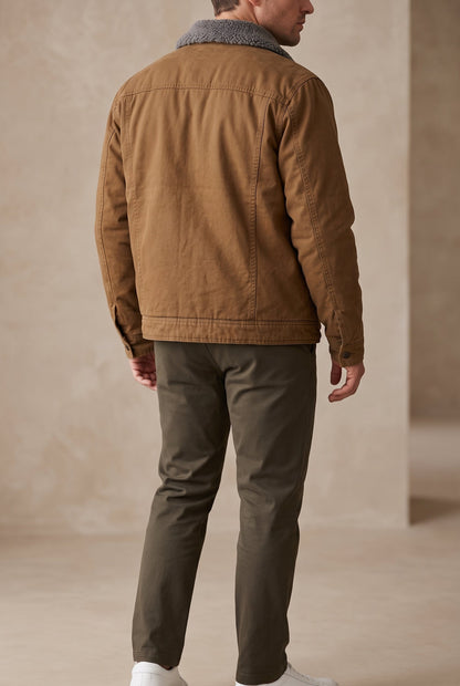Back view of a model in the tan jacket with fleece collar, stitched seams and olive trousers 3