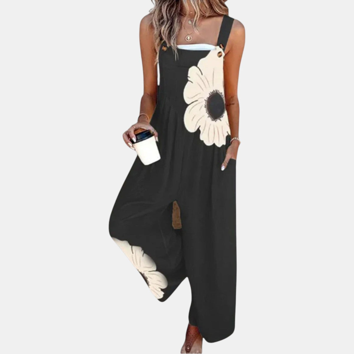 Model wearing black wide-leg dungarees with a large cream flower, holding a coffee cup, front view 1