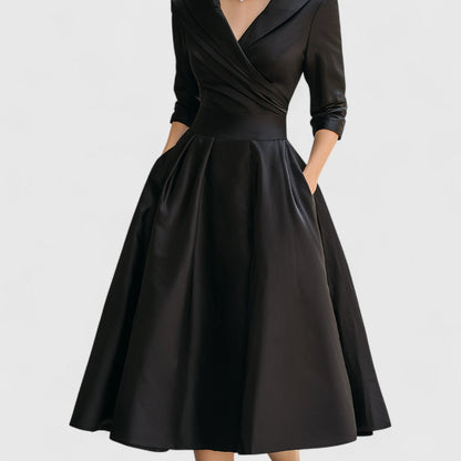 Black midi dress shown on a plain pale background, cropped to highlight the wrap bodice, waistband and full pleated skirt. 11