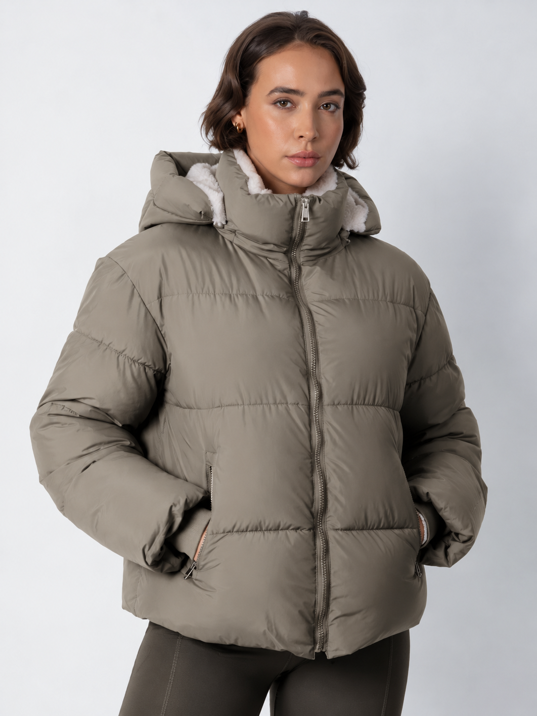 Front view of a taupe-grey puffer jacket zipped up with the hood up and cream fleece visible inside 18