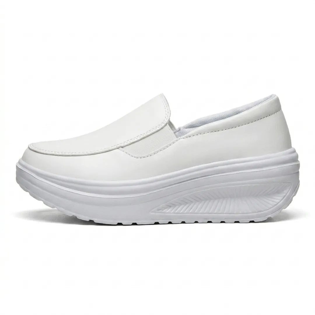 White faux-leather slip-on shoe in side profile, showing the elastic panel and curved wedge sole 10