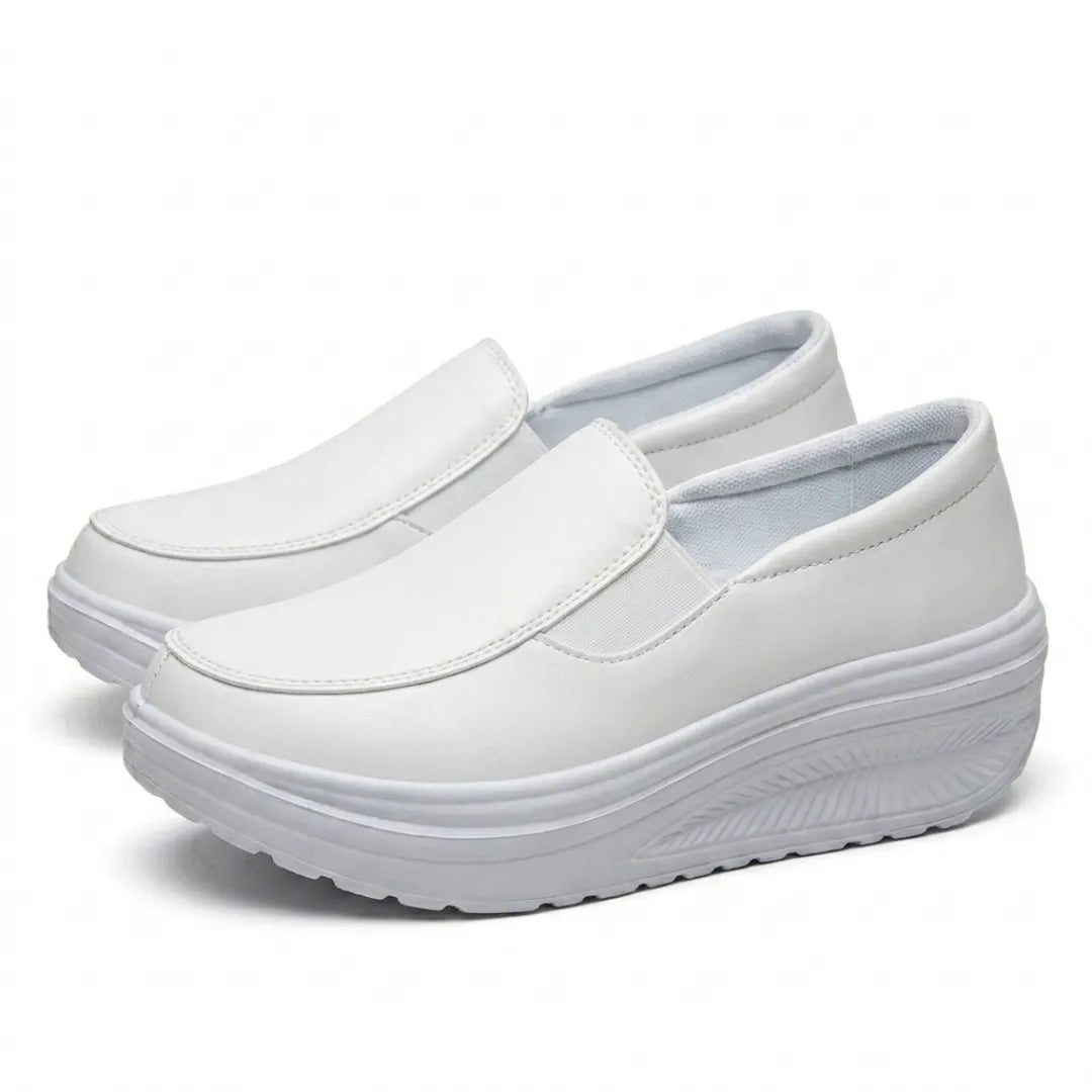 Pair of white slip-on wedge shoes angled from the front, with soft padded lining visible 16