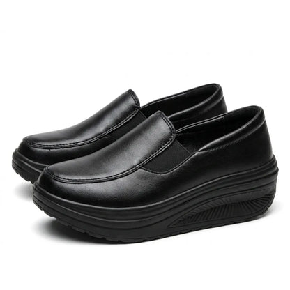 Pair of black slip-on wedge shoes angled from the front, with stitched toe seam and elastic gusset 7