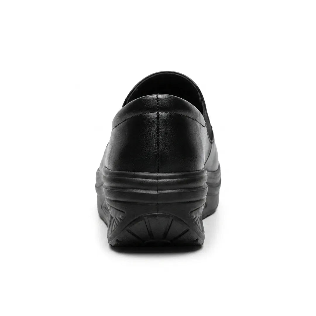 Black slip-on shoe seen from behind, showing the heel stitching and curved wedge sole 9
