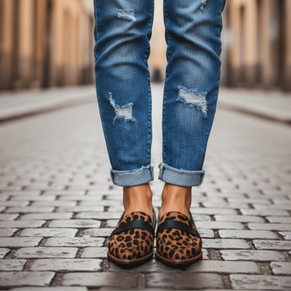 Leopard-print loafers with a black strap, worn with distressed, turned-up blue jeans on a cobbled street. 3