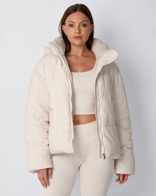 Model in a cream puffer jacket worn open over a matching ribbed crop top and leggings, front view 1