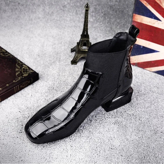 Black glossy crocodile-effect ankle boot with elastic side panel, shown at three-quarter angle on grey carpet 1