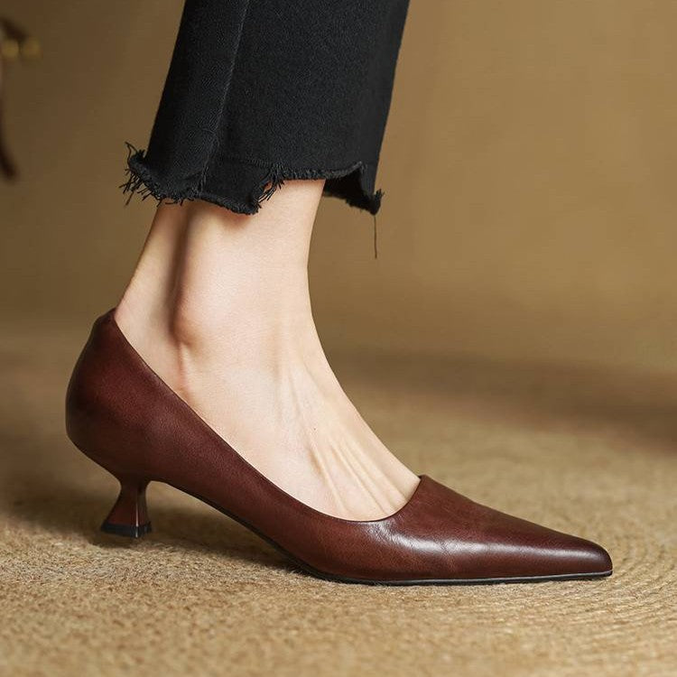 Side view of a brown leather pump worn with black frayed trousers, showing the flared heel 19