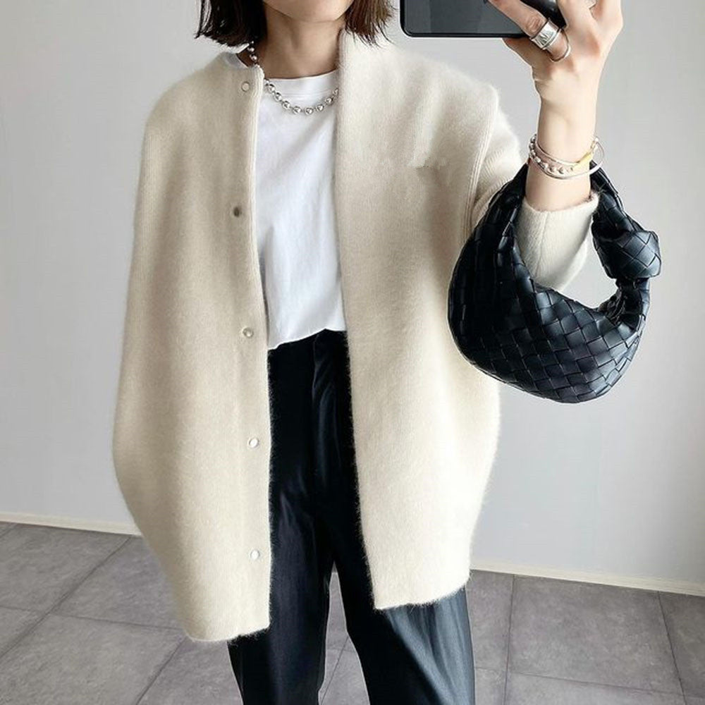 Model in the cream cardigan with open front, white tee and black trousers, holding a woven black bag 2