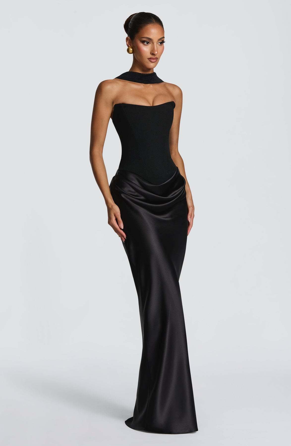 Black strapless corset maxi dress with draped choker neckline, shown at a three-quarter angle on a model 22