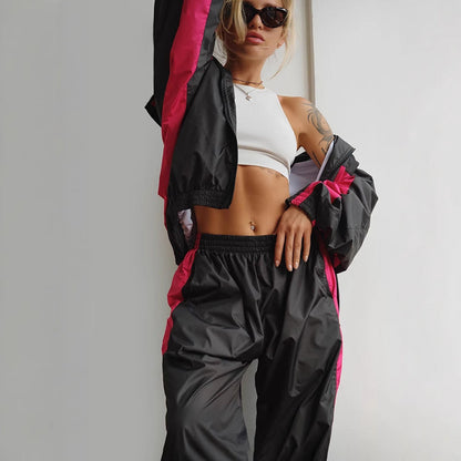 Close-up of a black windbreaker set with bright pink side panels, worn over a white ribbed crop top with elasticated waistband. 10