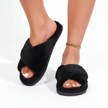 Black faux-fur crossover slippers worn by a model, one foot angled to show the dark sole 3