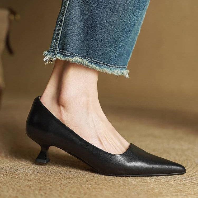 Side view of a black leather pump worn with frayed jeans, showing the flared kitten heel 14