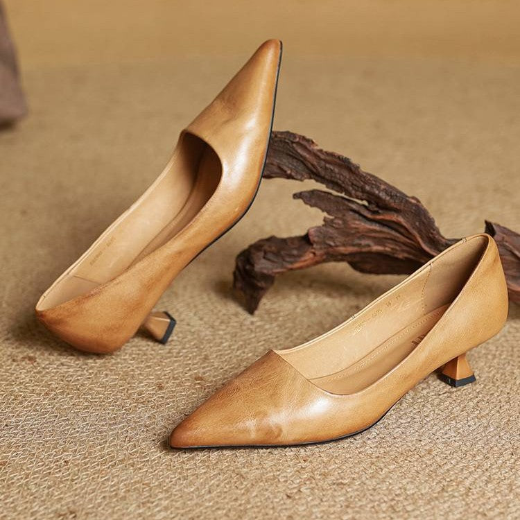 Pair of tan leather pumps on woven matting beside a piece of driftwood, one tilted upright 5