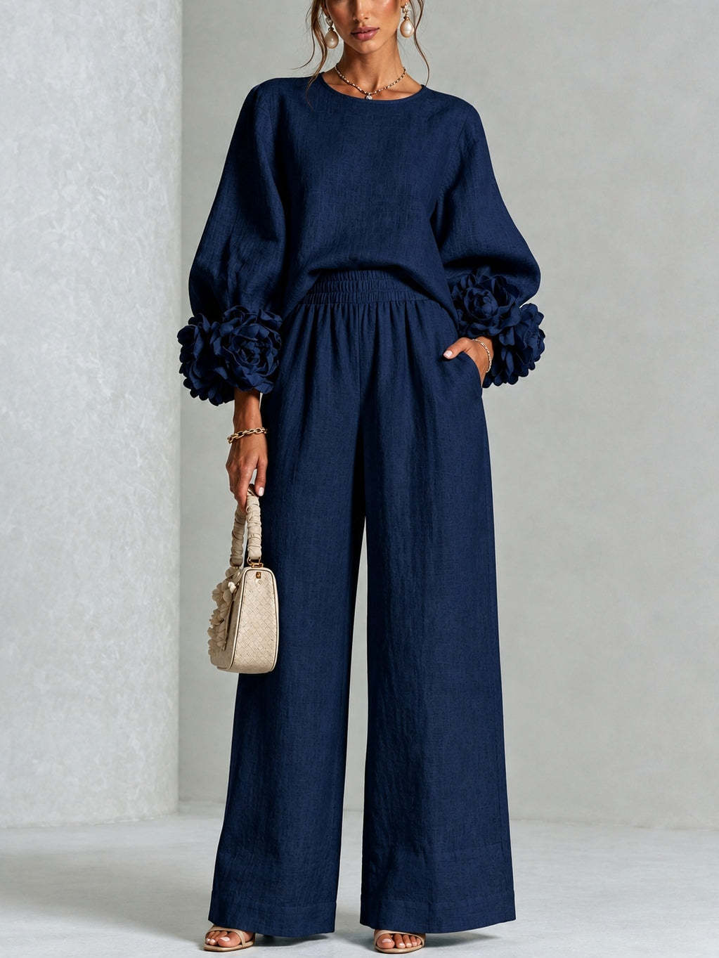 Model standing front-on in the navy blue version, with dark fabric flowers at each cuff 6