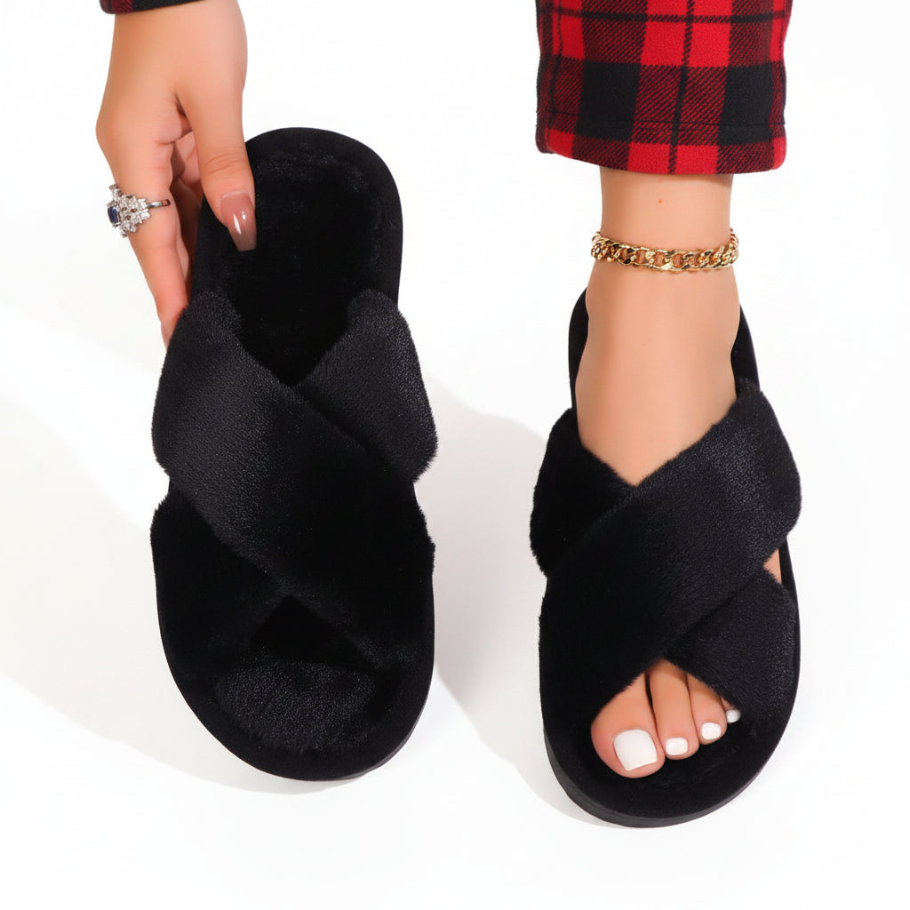 Black fluffy crossover slippers, one worn with red tartan trousers and one held up in hand 9