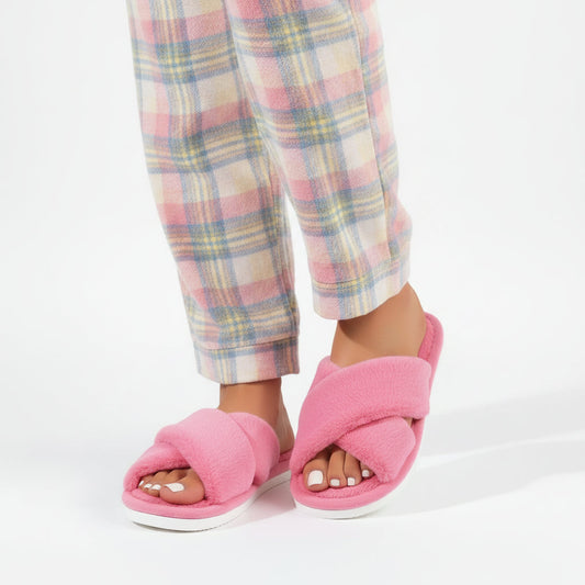 Pink plush crossover slippers worn with pastel checked pyjama trousers, seen from the front 2