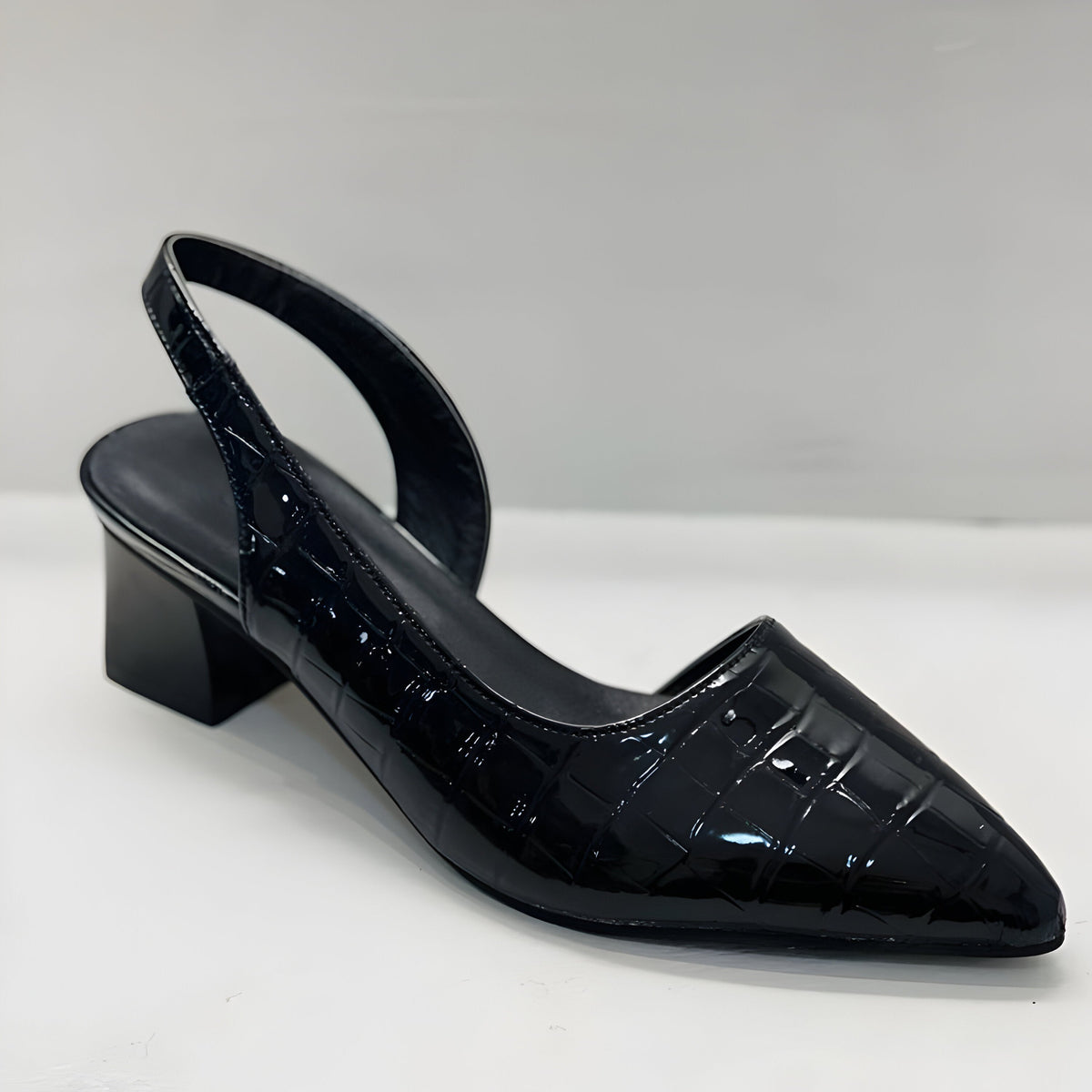 Single black patent crocodile-effect slingback heel with pointed toe and low block heel, seen from the front on white. 4