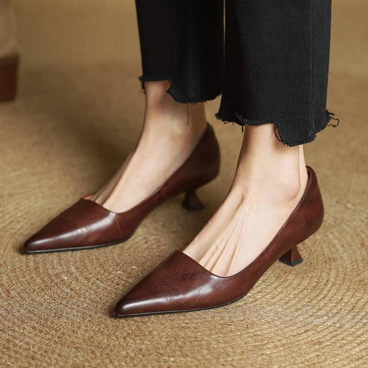 Brown leather kitten heels worn with black frayed-hem trousers, seen from the front on woven matting 18