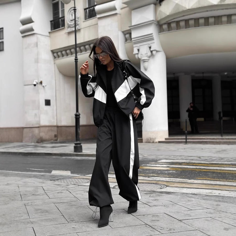 Model walking down a street in a black windbreaker set with white chevron panels and white side stripes on the trousers. 5