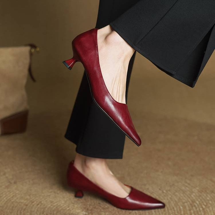 Red leather kitten heels worn with wide black trousers, one foot lifted to show the heel 9