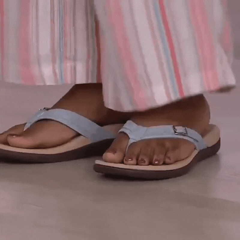 Woman in a pastel striped skirt wearing light blue buckled thong sandals on a pale floor 16