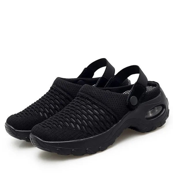Pair of all-black mesh clogs with elastic heel straps, snap buttons and a chunky air-cushion sole, on a white background. 2