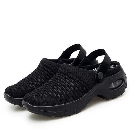 Pair of all-black mesh clogs with elastic heel straps, snap buttons and a chunky air-cushion sole, on a white background. 2