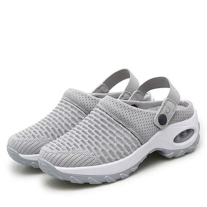 Pair of light grey mesh slip-on clogs with heel straps, snap buttons and a white air-cushion sole, shown on a plain background. 1