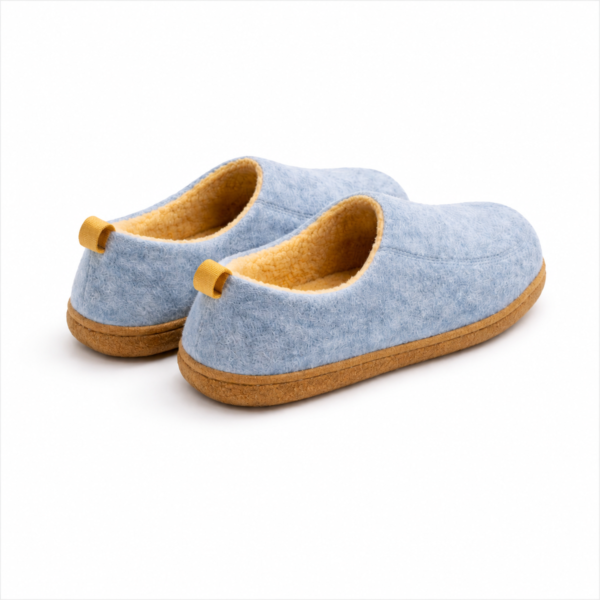 Rear three-quarter view of the light blue slippers, showing the yellow heel pull loops, fleece-lined openings and tan hard soles. 2