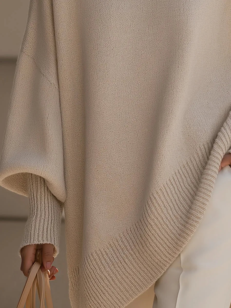 Close-up of the cream jumper's ribbed sloping hem and cuff, with a hand holding a handbag 3