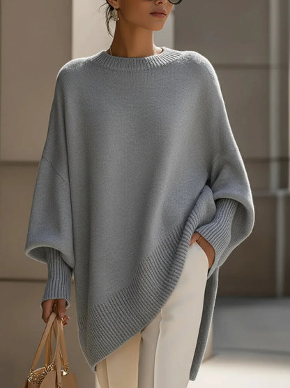 Model wearing the light grey version of the jumper with white trousers and a handbag 9