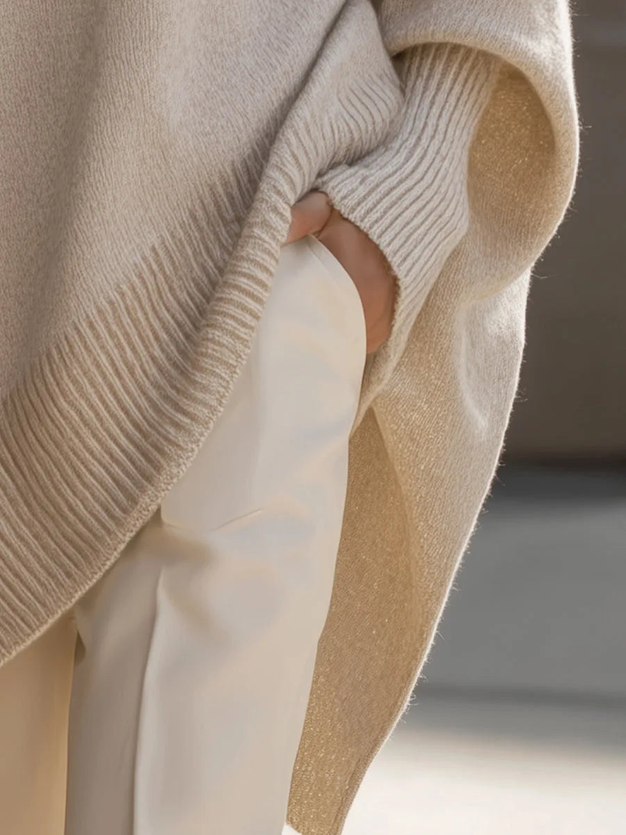 Detail of the side slit and ribbed hem on the cream jumper, hand tucked into trouser pocket 5