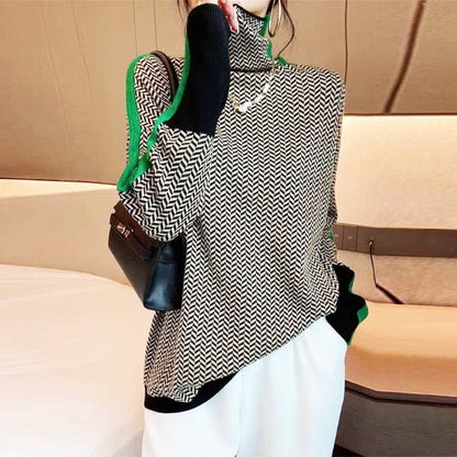 Model wears the black and white herringbone high-neck jumper with green side stripes, white trousers and a black handbag on her shoulder. 2