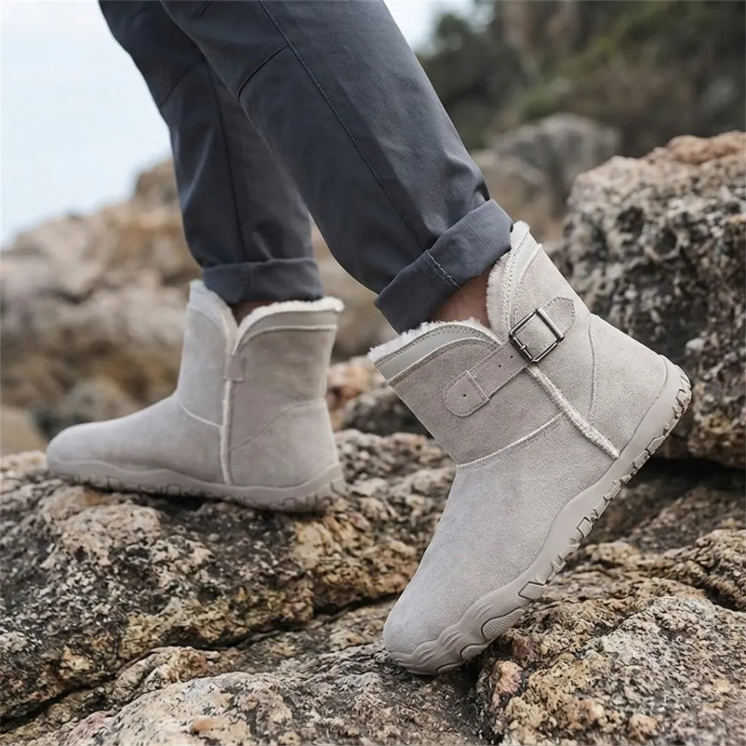 Person in rolled-up trousers wearing light grey fleece-lined boots while stepping over rocks outdoors 29