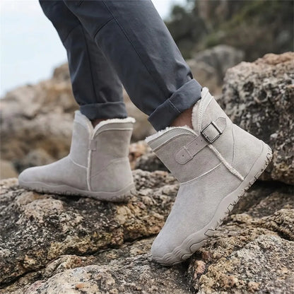 Person in rolled-up trousers wearing light grey fleece-lined boots while stepping over rocks outdoors 29