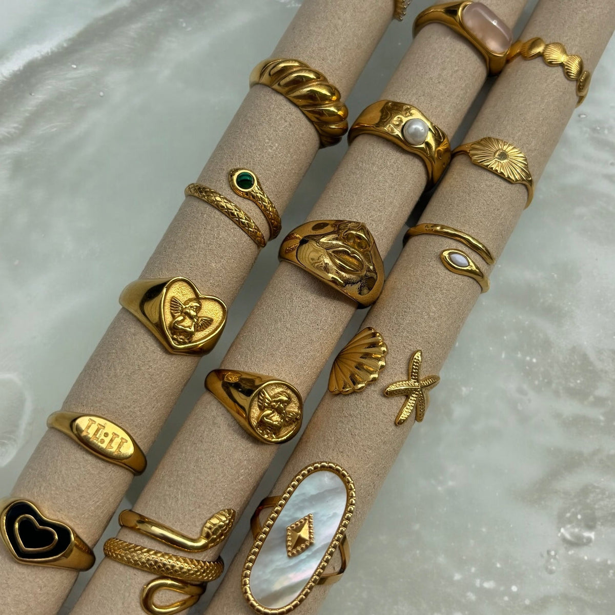 Heart cherub ring displayed on beige tubes among other gold-tone rings, including snake, shell and pearl styles 5
