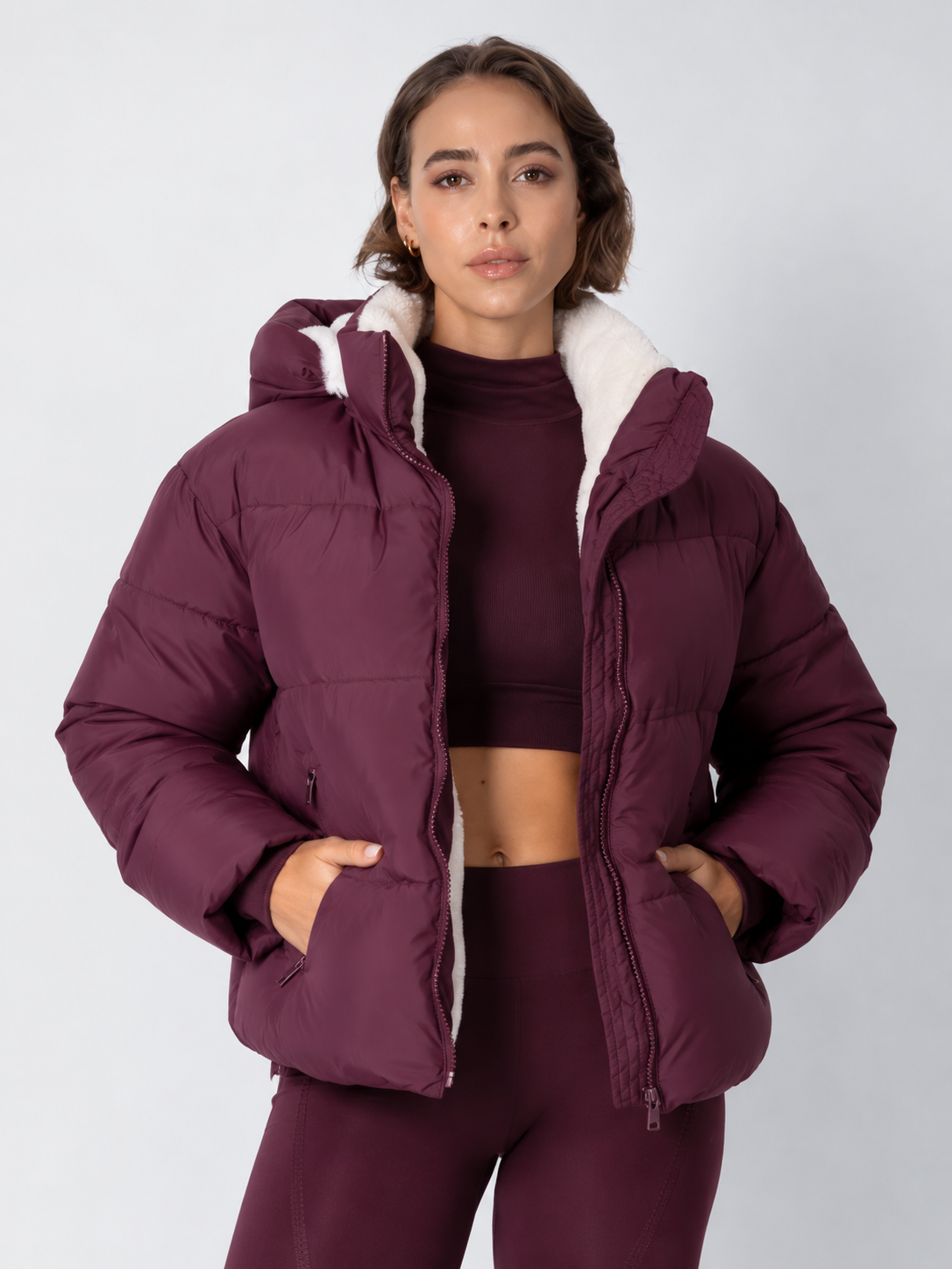 Model in a deep burgundy puffer jacket worn open over a matching high-neck crop top, hands in the pockets 16
