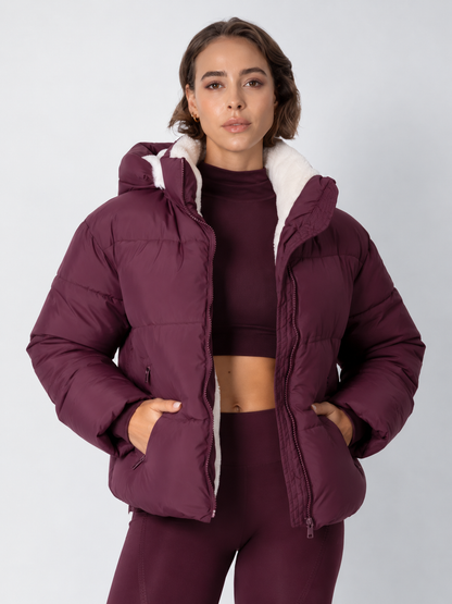 Model in a deep burgundy puffer jacket worn open over a matching high-neck crop top, hands in the pockets 16