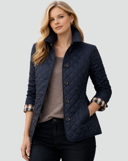 Model wearing the navy quilted jacket with a check cuff lining, worn open over a taupe top and dark jeans, hand in pocket. 5