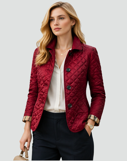 Model wearing the burgundy quilted jacket over a white blouse and navy trousers, with a gold watch and handbag, looking away from the camera. 6