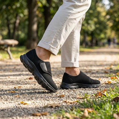 Black mesh shoes with black soles worn by a walker in light trousers on a gravel path 11