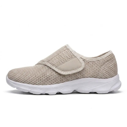 Side view of a beige mesh shoe with white sole and hook-and-loop strap over the instep 28