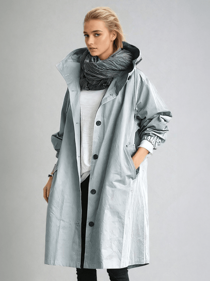 Model wears the coat in a pale glossy blue-grey, open over a white top and scarf 5