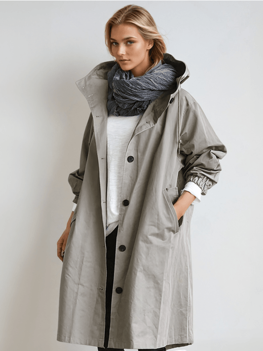 Model wears the long hooded coat in grey, unbuttoned over a white top with a scarf 1