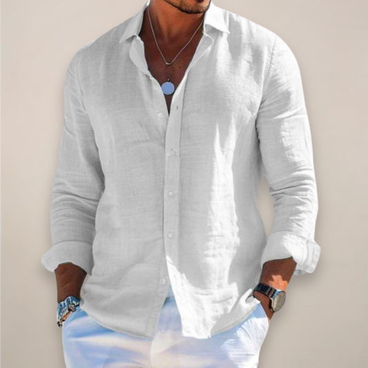 Model wearing the white version of the shirt, buttoned with sleeves rolled up, hands in pockets of white trousers. 2